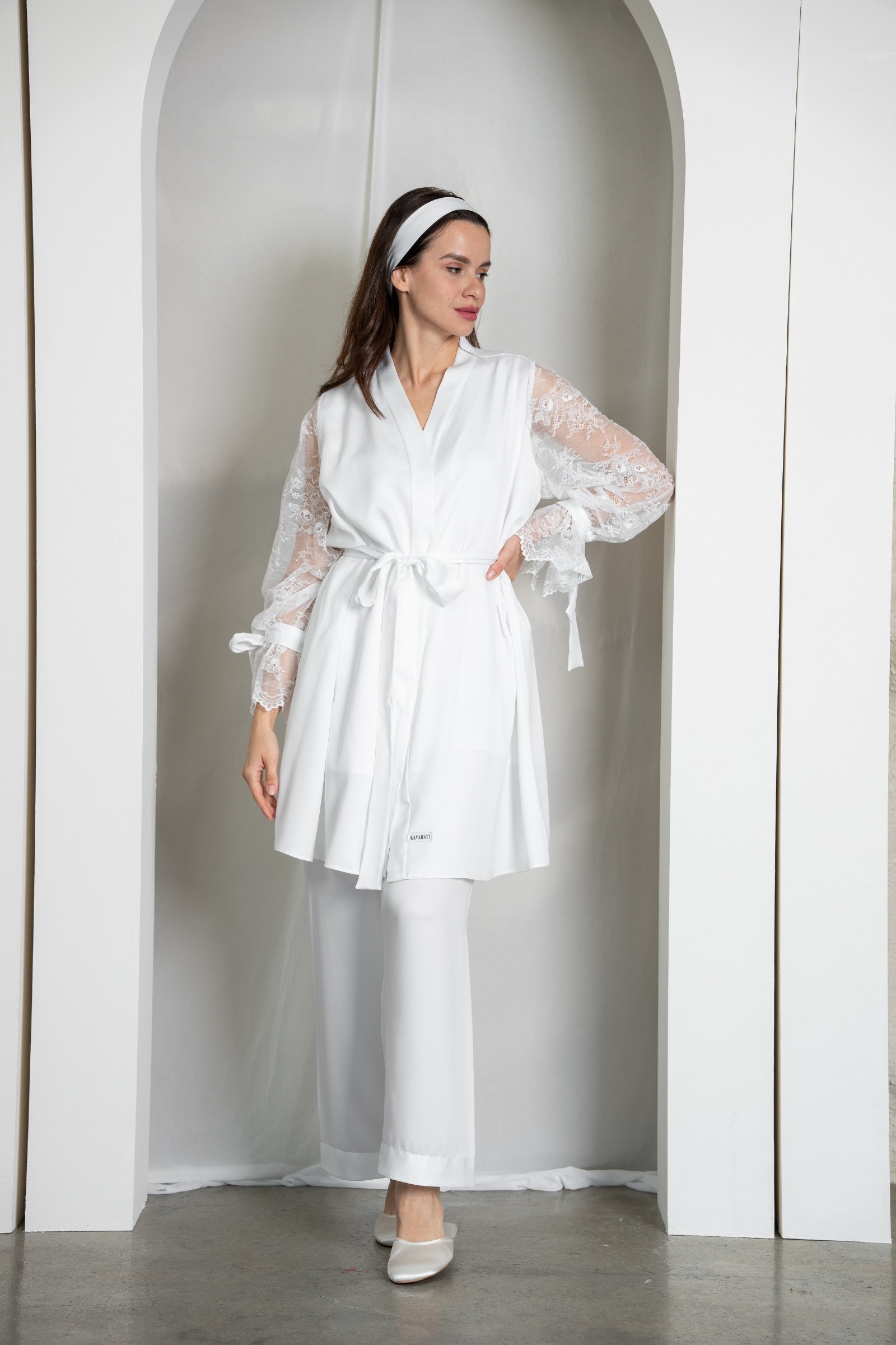 Woman wearing a white robe and pants in a minimalistic setting