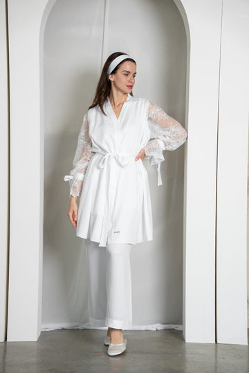 Woman wearing a white robe and pants in a minimalistic setting